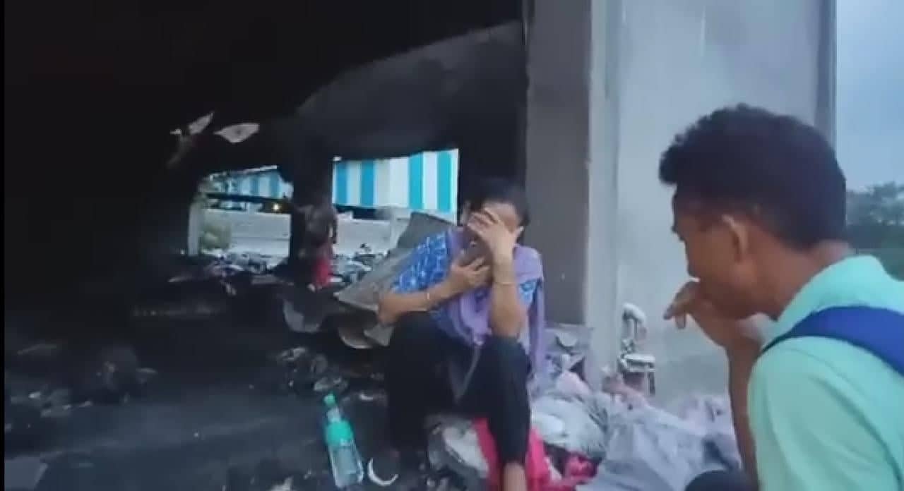 Tibetan woman seated near the storage as another man looks on (screengrab)